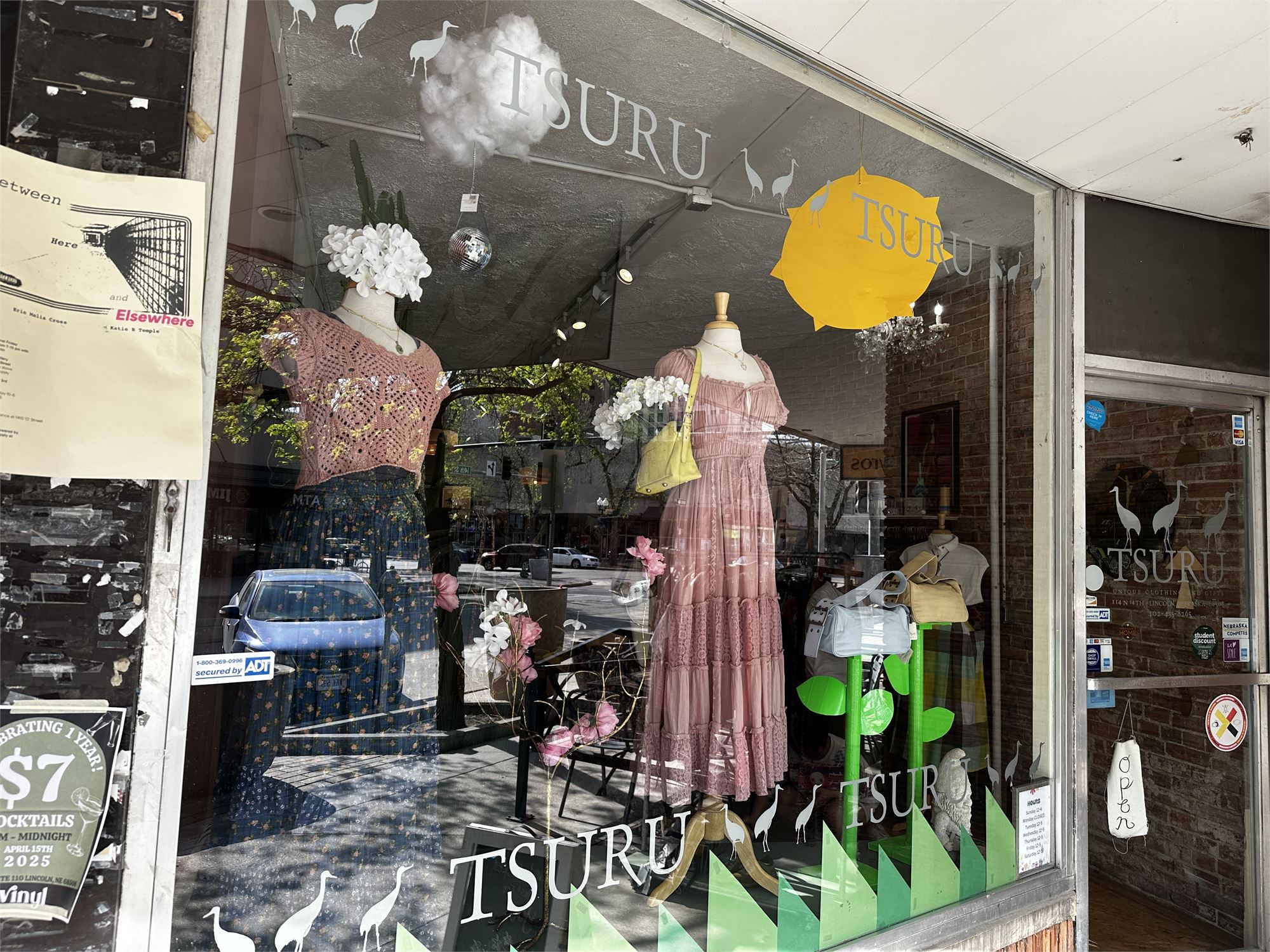 Tsuru boutique window display with dressed mannequins, white hydrangeas, and a yellow Tsuru umbrella.